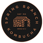Spring Branch Kombucha logo featuring a circular black background with a stone house design in copper tones. The text ‘Spring Branch Kombucha’ encircles the house, along with ‘SGF MO’ and ‘MMXVII’ in smaller font.
